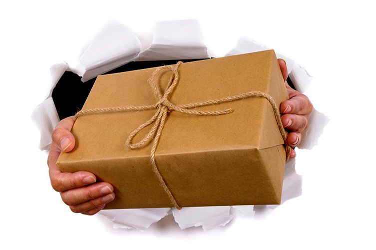 Man hands delivering or giving parcel through torn white paper background